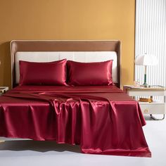 a bed with red sheets and pillows in a room