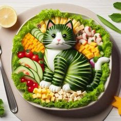 a cat made out of fruits and vegetables on a plate with silverware next to it