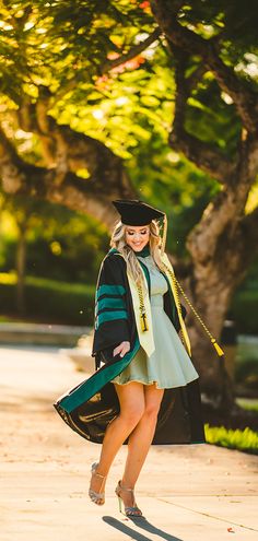 a woman in a graduation gown is walking down the street with her hand on her hip