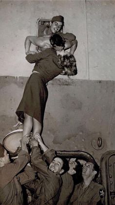 an old black and white photo of a woman on top of men