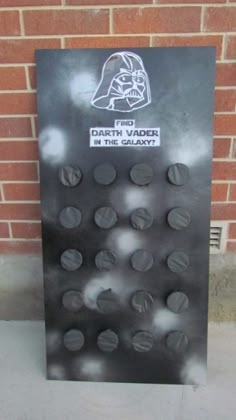 a darth vader sign on the sidewalk next to a brick wall that says darth vader is in the galaxy