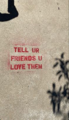 the words tell us friends u love them written in red ink on a concrete surface