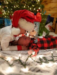 a baby laying on top of a bed next to a christmas tree