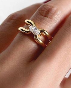 a woman's hand holding a gold ring with a diamond in the shape of a heart