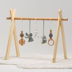 two stuffed animals are hanging from a wooden frame with rings on it's strings