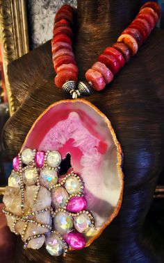 After a re-stringing repair, this piece is now ready for a new home! A 7" x 5" hot pink and Fuchsia Brazilian agate hosts a rough white quartz cluster, faux clear and pink crystals and rows of silver aurora borealis rhinestones! The pendant is suspended from an agate rondelle statement necklace which measures 21". The reddish-pink agates are polished on one side and rough on the other. Each agate is spaced with an ornate silver tone metal bead. Flanking the pendant are rhinestone rondelles and silver tone stamped tribal bi-cone beads. The back is finished with more tribal beads, rhinestone rondelles, frosted pink druzy agates and clear faceted crystals. Closes with a fancy silver tone hook and eye. This is a very dense and heavy piece so please know your tolerance before you buy. From the Artisan Pink Gemstone Beads Jewelry, Unique Pink Gemstone Beads Jewelry, Artisan Pink Gemstone Jewelry, Pink Agate Gemstone Jewelry, Unique Pink Ruby Jewelry, Rocker Chic Accessories, Statement Necklace Wedding, Brazilian Agate, Unique Pendant Necklace