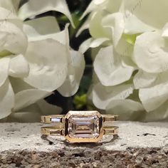 an engagement ring sitting on top of a stone slab next to white hydrangeas