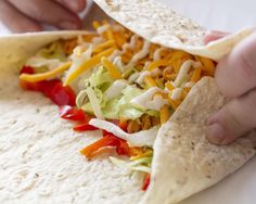 a tortilla with shredded cheese, lettuce and red peppers