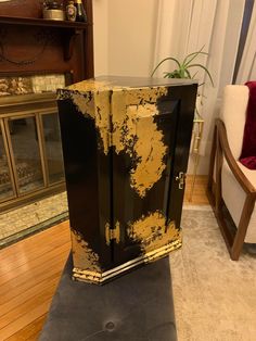 a black and gold cabinet sitting on top of a wooden floor