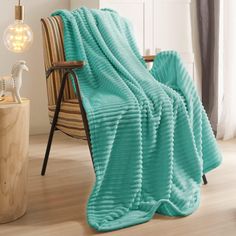 a blanket that is sitting on top of a chair in front of a table with a lamp