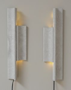 two white wall lights mounted to the side of a wall