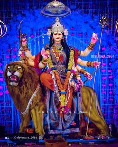 a statue of goddess sitting on top of a lion in front of a blue background