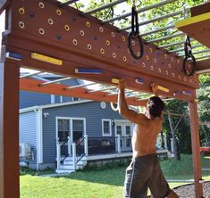 a man is working on an outdoor climbing wall in the yard with his hands and feet