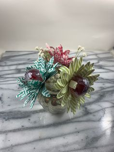 a glass vase filled with flowers on top of a marble counter topped with green and red ribbons