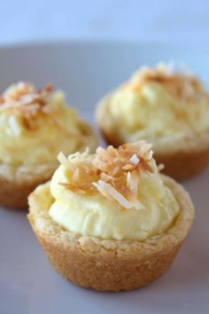 three cupcakes with white frosting and toppings on top are sitting on a plate