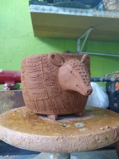 a clay animal sitting on top of a piece of wood in a workshop area with other tools