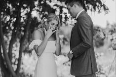 a man and woman standing next to each other in front of trees talking on their cell phones