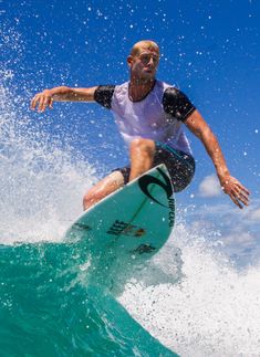 a man riding a surfboard on top of a wave in the ocean with blue sky