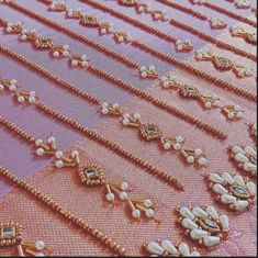 several rows of gold and pearled necklaces on a pink fabric with white beads