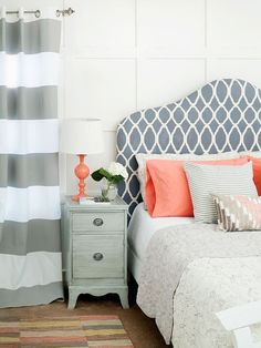 a white bed with orange and gray pillows