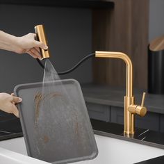 a person is washing their hands in a kitchen sink with a gold faucet