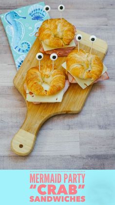 some food is on a wooden board with googly eyes in the shape of croissants