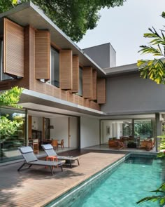 a house with a swimming pool in front of it and wooden shutters on the side