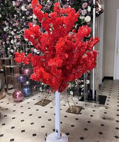 a bunch of red flowers are in a vase on a stand with black and white checkered flooring