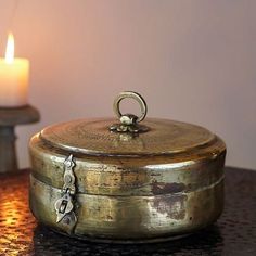 a candle sitting on top of a table next to a metal container with a lid