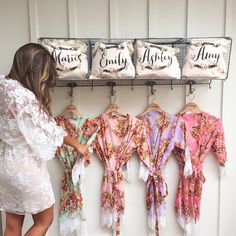 a woman is looking at some robes hanging on a rack in front of the wall