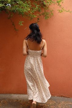 a woman standing in front of a red wall with her back turned to the camera