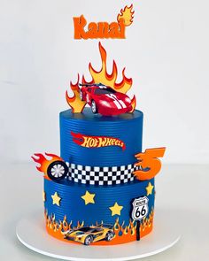 a three tiered cake decorated with cars and fire on it's sides, in the shape of a race car