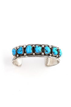 This Marie Thompson Kingman Turquoise Row Cuff is the perfect bracelet for a large wrist. Navajo silversmith, MarieThompson, has created this traditional row bracelet with 7 genuine Kingman Turquoise stones. She added handmade sterling silver beads between each stone and hand-stamped Navajo designs along the edge of the bracelet. The sterling silver was oxidized to bring out the details and give this cuff a vintage look. Hallmarked "MT" and stamped "Sterling". Fits 7.25" wrist, adjustable Navajo Designs, Silver Eagles, Turquoise Stones, Kingman Turquoise, Handmade Sterling Silver, Sterling Silver Bead, Turquoise Stone, The Edge, Silver Beads