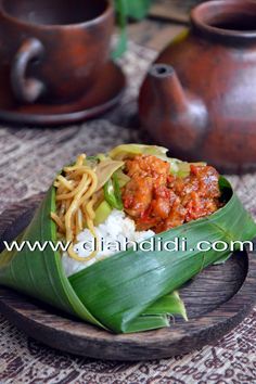 a plate with noodles, meat and vegetables on it next to two teapots