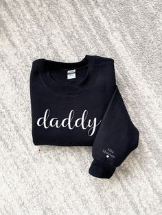 Our mama and daddy sweatshirts are personalized with the children's names on their wrist/sleeve making it a wonderful gift for Mother's Day, Father's Day, birthday, Christmas or just a special way to show off their love for their child(ren). These sweatshirts can be customized to change the name from mama and daddy to any special way the little ones call them!  ❤️       ** LISTING IS FOR ONLY ONE SWEATSHIRT -  CHECK OUT WITH 2 TO COMPLETE THE LOOK! **   ADULT SWEATERS ARE UNISEX  SMALL - 2XLARGE Family Matching Crew Neck Sweatshirt For Father's Day, Mother's Day Black Crew Neck Sweatshirt, Relaxed Fit Name Print Sweatshirt Gift, Father's Day Crew Neck Sweatshirt As Gift, Father's Day Gift Crew Neck Sweatshirt, Family Matching Custom Text Sweatshirt, Father's Day Cotton Sweatshirt With Name Print, Personalized Cotton Sweatshirt As A Gift, Personalized Cotton Sweatshirt As Gift