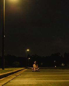 a person sitting on the ground under a street light