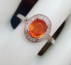 1.73 carat weight, 7x6mm, rare natural orange Spessartite (Spessartine) garnet ring with white topaz halo. Ring size 7. Sterling silver 925. Rhodium plated. This listing is for the ring shown in photos and there are no additional sizes or quantities available. Spessartine Garnet, Art Promotion, Garnet Jewelry, Garnet Ring, Etsy Art, Pretty Rings, Garnet Rings, Halo Ring, White Topaz