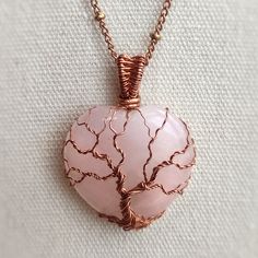 This Tree of Life pendant is handmade with a heart-shaped natural rose quartz stone. The metal part is bare copper. • Pendant size : H 2.8 x W 1.3 cm 🎁 This pendant comes with a free 20" copper chain necklace. Ready to wear or give as a gift. ✨ One-of-a-kind item ✨ There is only one of these. You will get the exact pendant as seen in the photos. CARE INSTRUCTION • Wire-wrapped jewellery is delicate, please handle it with care and avoid wearing it during activities that may bend the piece. • Aft Handmade Rose Gold Heart Pendant Jewelry, Rose Gold Rose Quartz Crystal Necklace Gift, Hand Wrapped Rose Gold Pendant Necklace, Rose Gold Hand Wrapped Necklace Gift, Spiritual Heart-shaped Rose Gold Jewelry, Spiritual Rose Gold Heart Jewelry, Wire Wrapped Rose Quartz Necklace Gift, Rose Quartz Wire Wrapped Necklace As Gift, Gift Rose Quartz Wire Wrapped Necklace