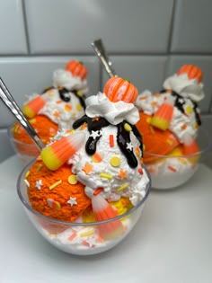 two bowls filled with halloween desserts on top of a white counter next to a tiled wall