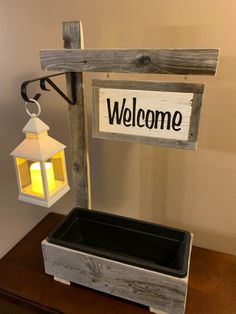 a welcome sign hanging from the side of a wooden wall next to a light fixture