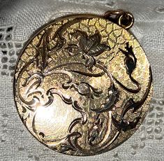 "Dating from the Art Nouveau period, early 1910s, this unique locket has a gorgeous botanical theme.  The flower blossom and flower buds are on curvy stems, accompanied by engraved leaves, all on a fancy, engine-turned background.  There is a blank shield at the bottom for monograming, but it was never used.  The back is shiny with a mirror finish.  The inside is signed \"1874\" over \"R.B.M.\" over \"ATRICE.\" The locket is by the R. B. MacDonald & Company, which was founded in 1874 in Attlebor Antique Engraved Flower Jewelry, Antique Flower Engraved Jewelry, Victorian Flower-shaped Collectible Jewelry, Victorian Flower Collectible Jewelry, Victorian Flower Jewelry Collectible, Victorian Flower Jewelry For Collectors, Unique Locket, Photo Locket, Flower Bud