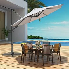 an outdoor table with chairs and an umbrella over it on a deck overlooking the ocean