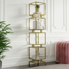 a gold shelving unit with books and plants on it next to a pink chair