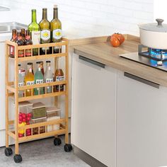 a kitchen area with a stove, counter and shelves filled with bottles on wheels next to a sink