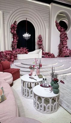 a living room filled with furniture and pink flowers on the wall next to a chandelier