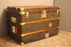 an old trunk sitting on top of a hard wood floor next to a white wall