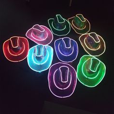 several different colored lights in the shape of cowboy hats on a black surface with dark background