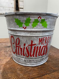 a metal bucket with christmas decorations painted on the side sitting on top of a wooden table