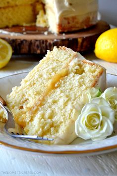 a slice of lemon cake on a plate with a fork and flowers next to it