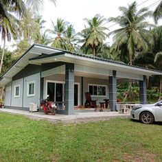 a small house sitting in the middle of a lush green field next to a parked car